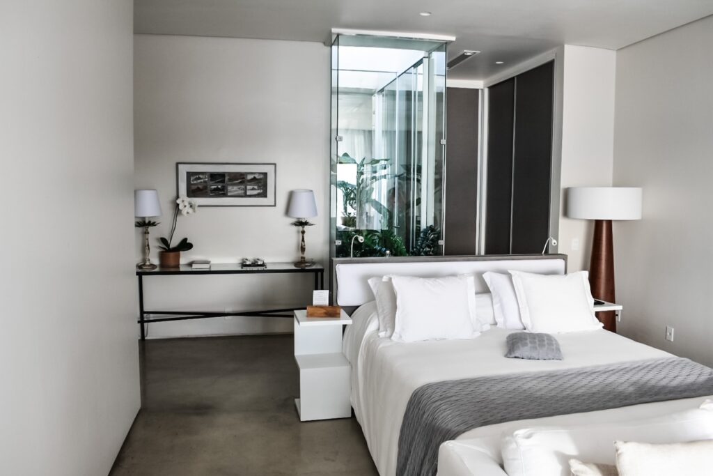 Modern white bedroom at Casas Brancas with glass wall and clean, serene design.
