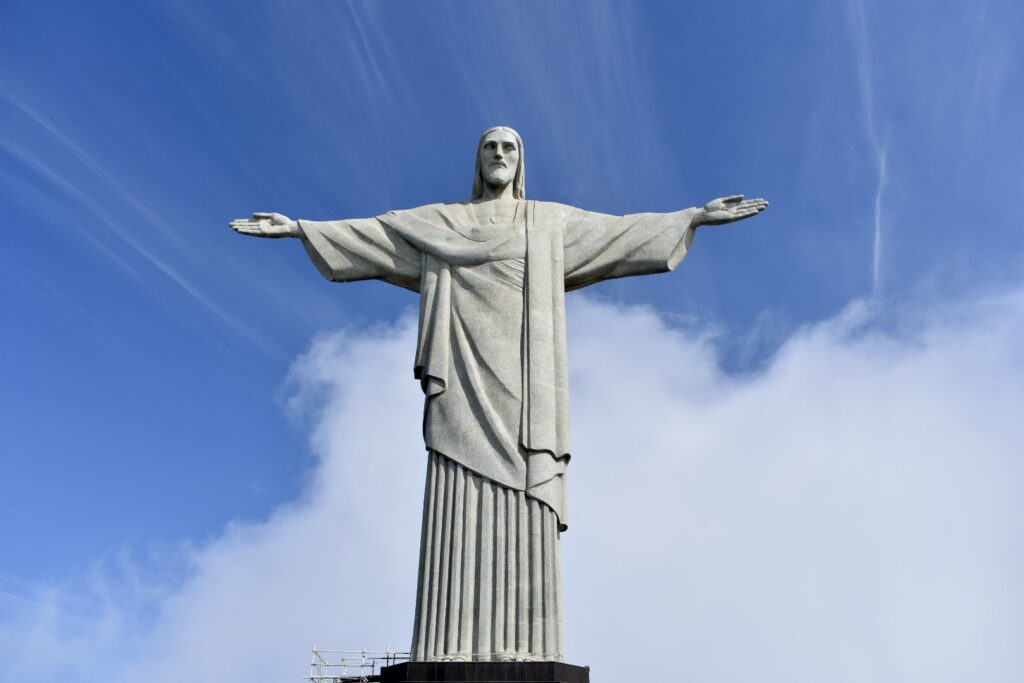 Christ the Redeemer statue in Rio de Janeiro standing tall against a bright blue sky with soft clouds.