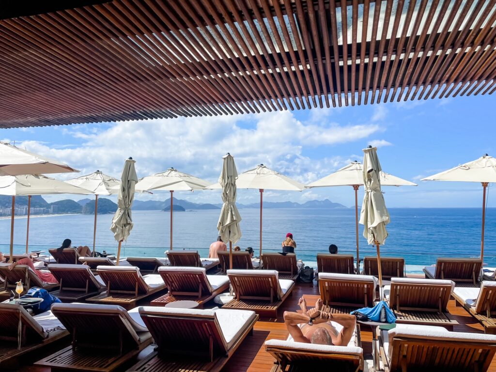 Sun loungers and umbrellas overlooking a bright blue ocean from Hotel Emiliano's modern terrace.