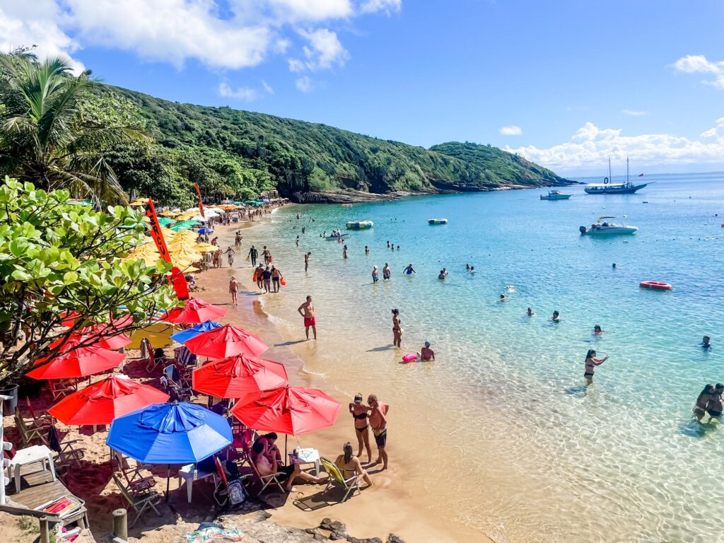 Colorful umbrellas and swimmers on a tropical beach with clear turquoise water.