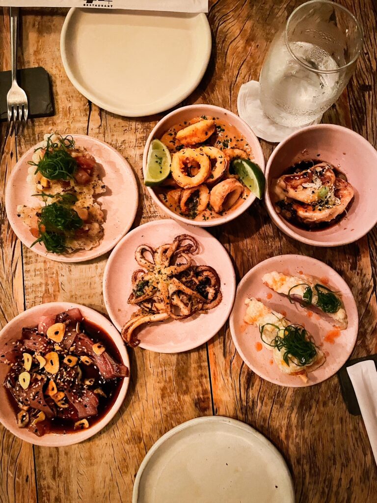 Assorted seafood tapas on a rustic wooden table with lime and garnish.