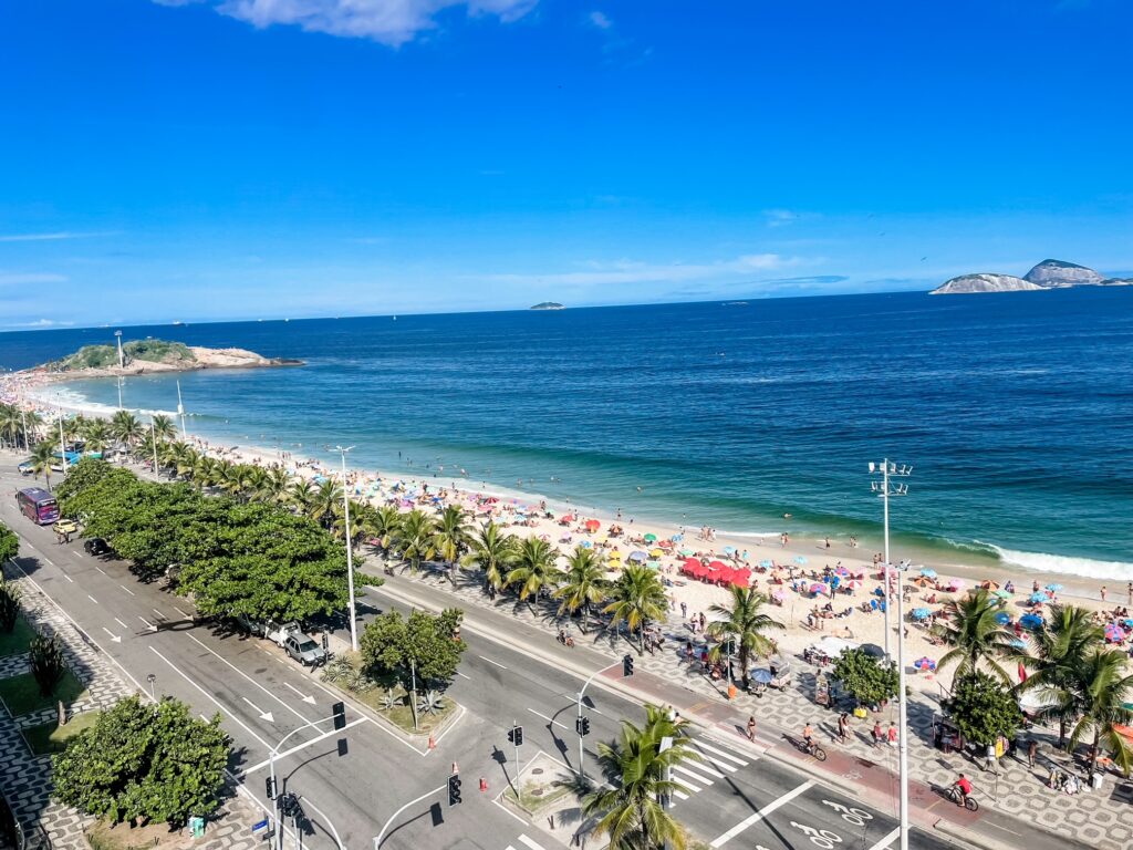 Aerial view of Copacabana Beach with palm trees, sunbathers, and turquoise water.