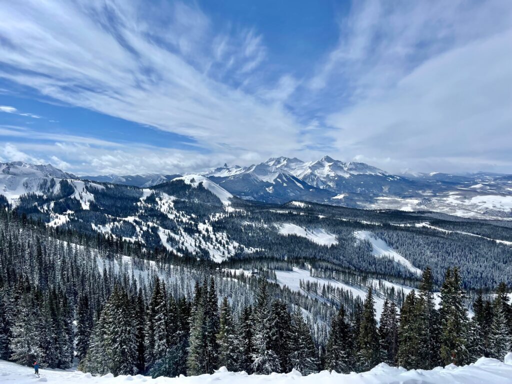 Panoramic view of Telluride’s snow-covered peaks and pine forests under a bright blue sky