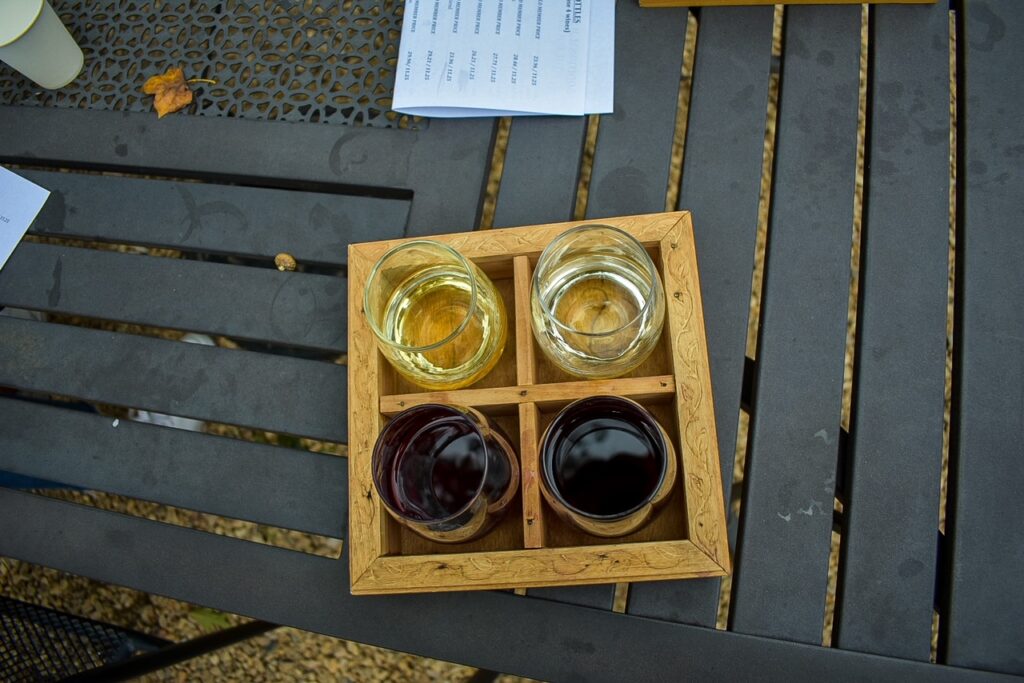 Four-glass wine tasting flight with white and red wines on a patio table.