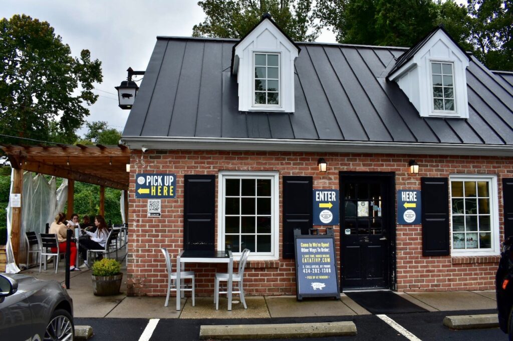 Brick building with black shutters and a patio seating area at Ivy Provisions café.