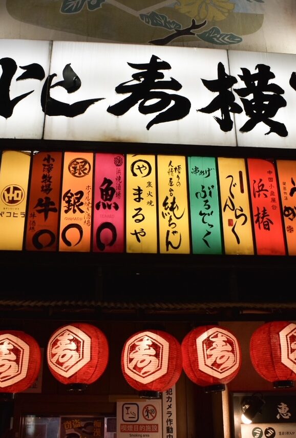 Colorful lantern-lit entrance to an izakaya alley in Ebisu, Tokyo, with Japanese signs glowing at night