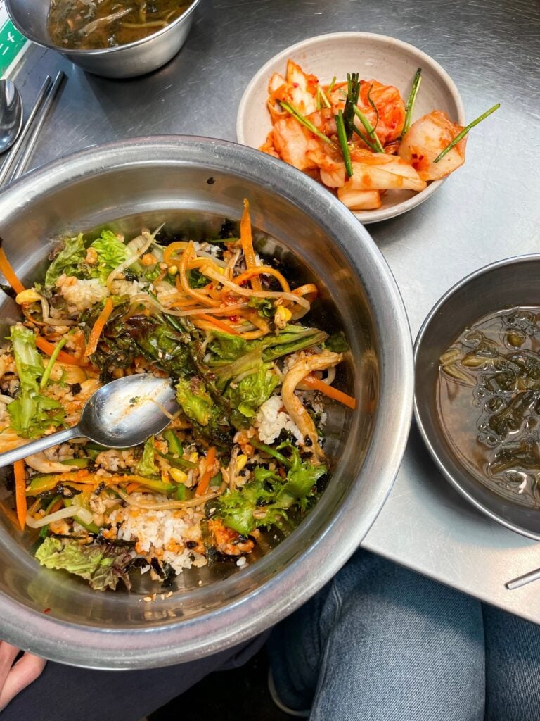 Bibimbap with vegetables, rice, and kimchi side dishes.