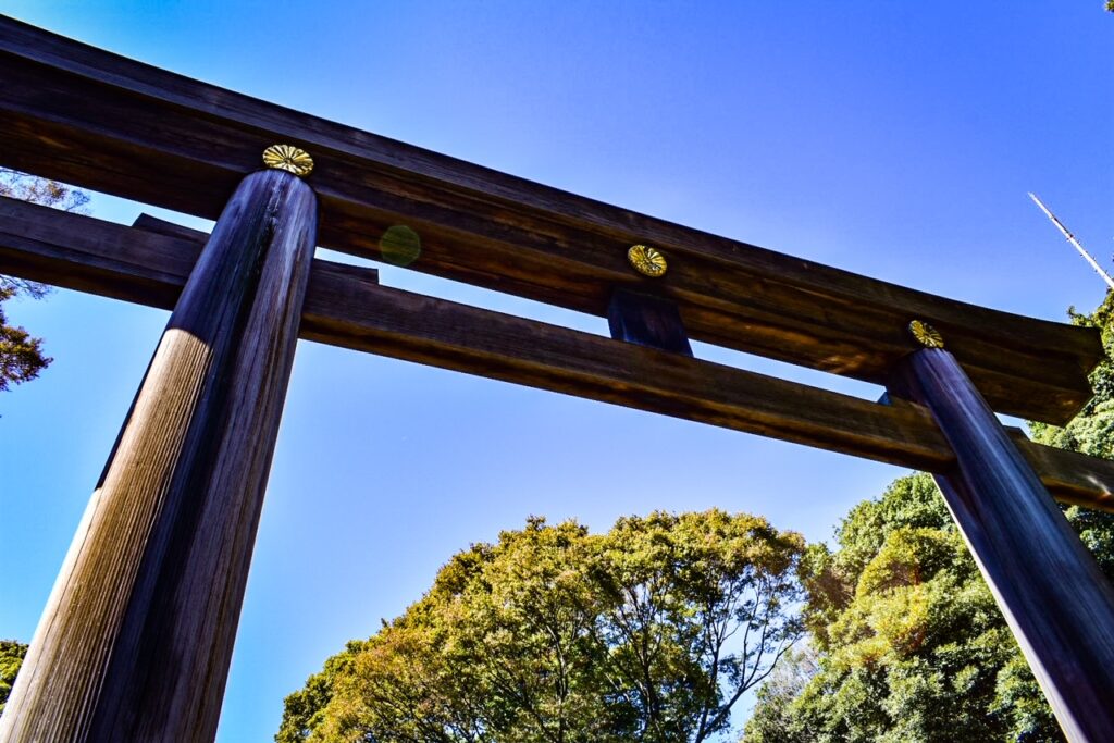 Wooden torii gate towering under a clear blue sky at Meiji-Jingu Shrine.