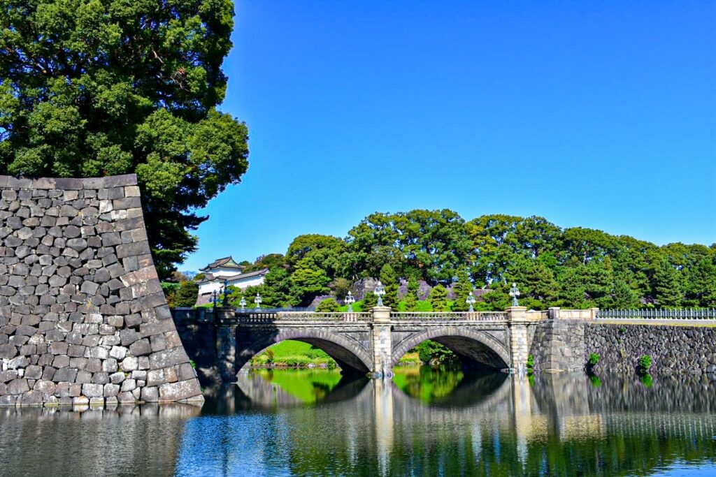 Stone bridge arching over the moat at Tokyo’s Imperial Palace under a clear blue sky.