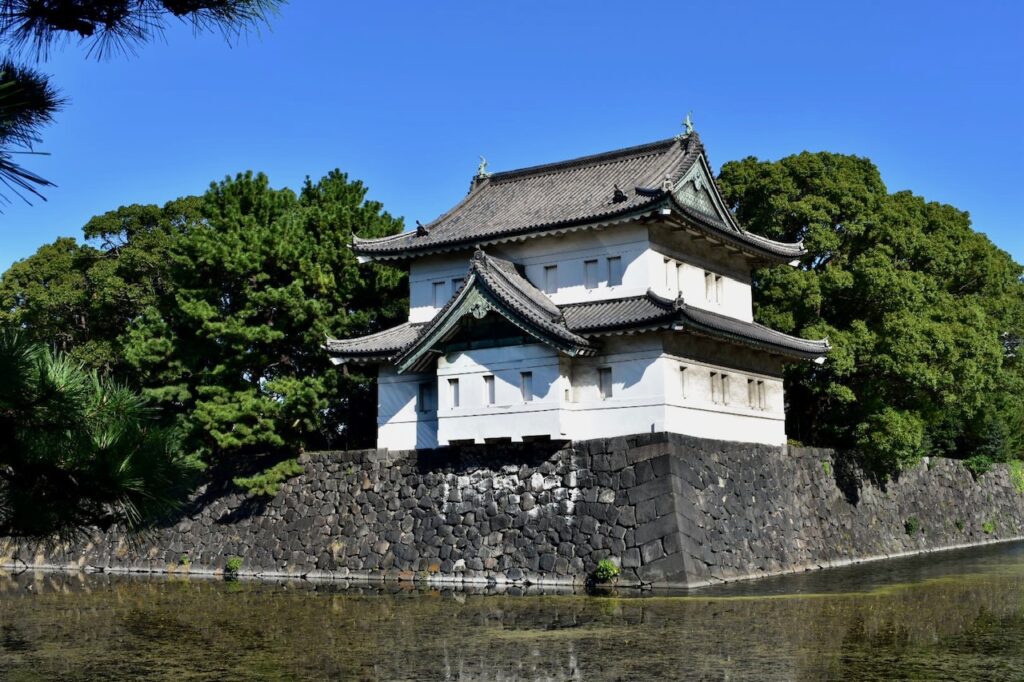 Traditional Japanese guard tower at the Imperial Palace surrounded by a stone wall and moat.