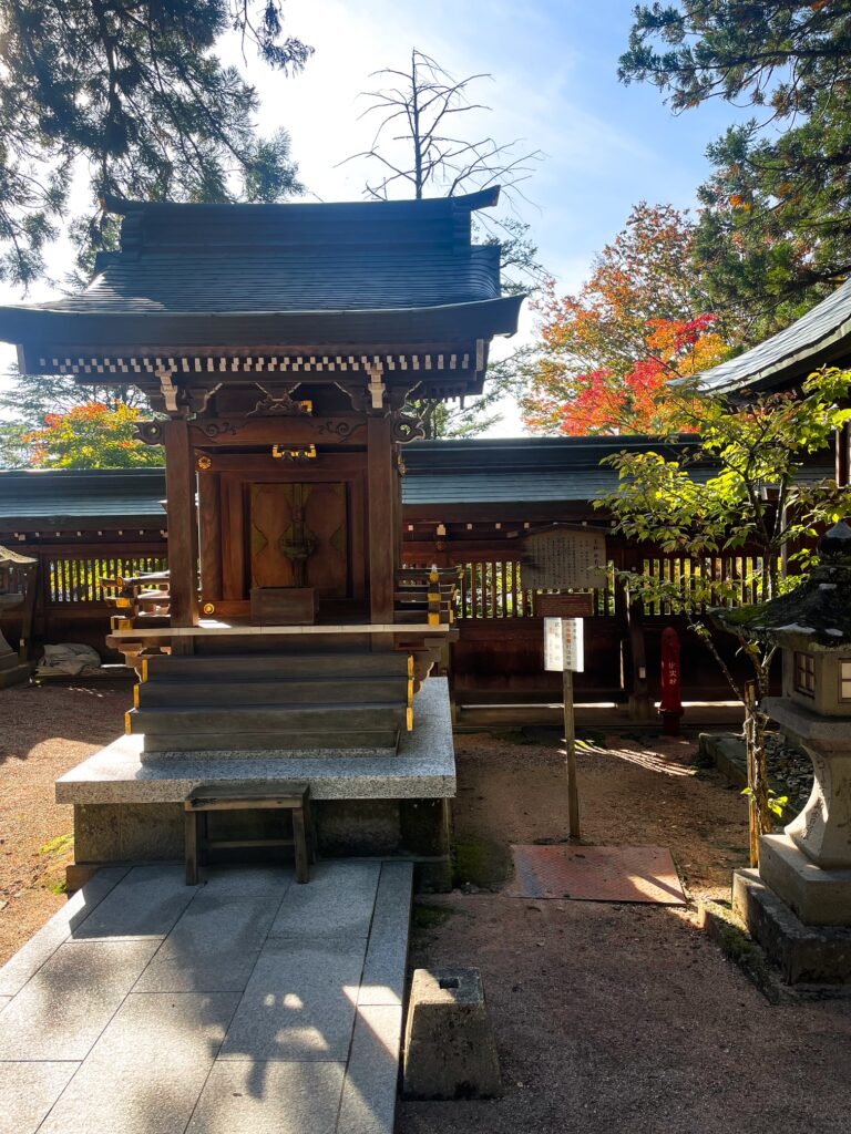 Wooden Shinto shrine building surrounded by trees and autumn foliage at Sakurayama Hachimangu Shrine.