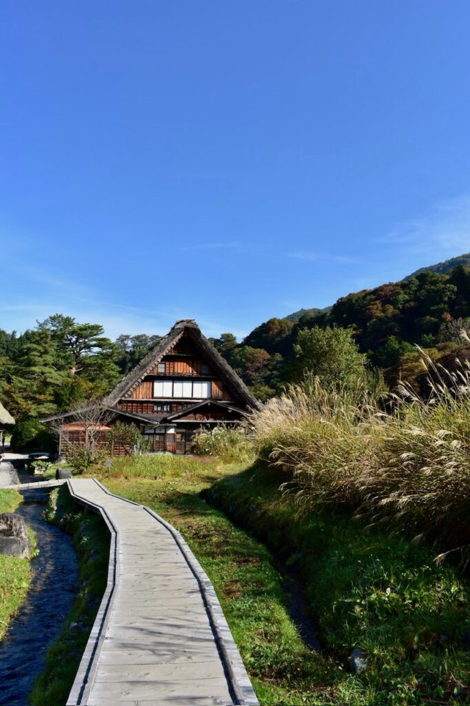Traditional thatched-roof house in Shirakawa-go, Japan, surrounded by lush greenery and mountain scenery