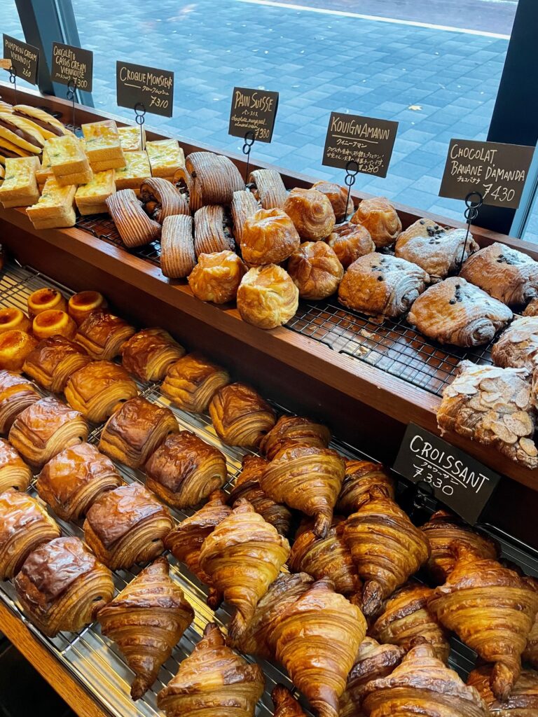 A display of golden, flaky croissants and assorted pastries neatly arranged in a bakery window.