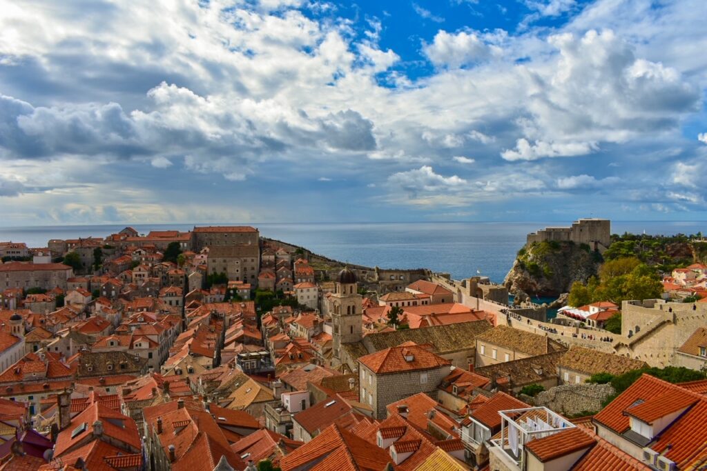 A panoramic view of Dubrovnik’s Old Town with terracotta rooftops and the Adriatic Sea glistening beyond the city walls.