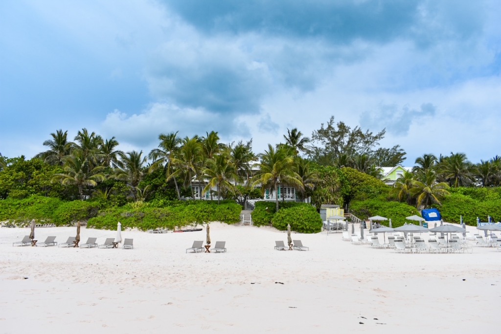 View of Ocean View Hotel on Harbour Island, Bahamas, from Pink Sand Beach with lounge chairs and palm trees