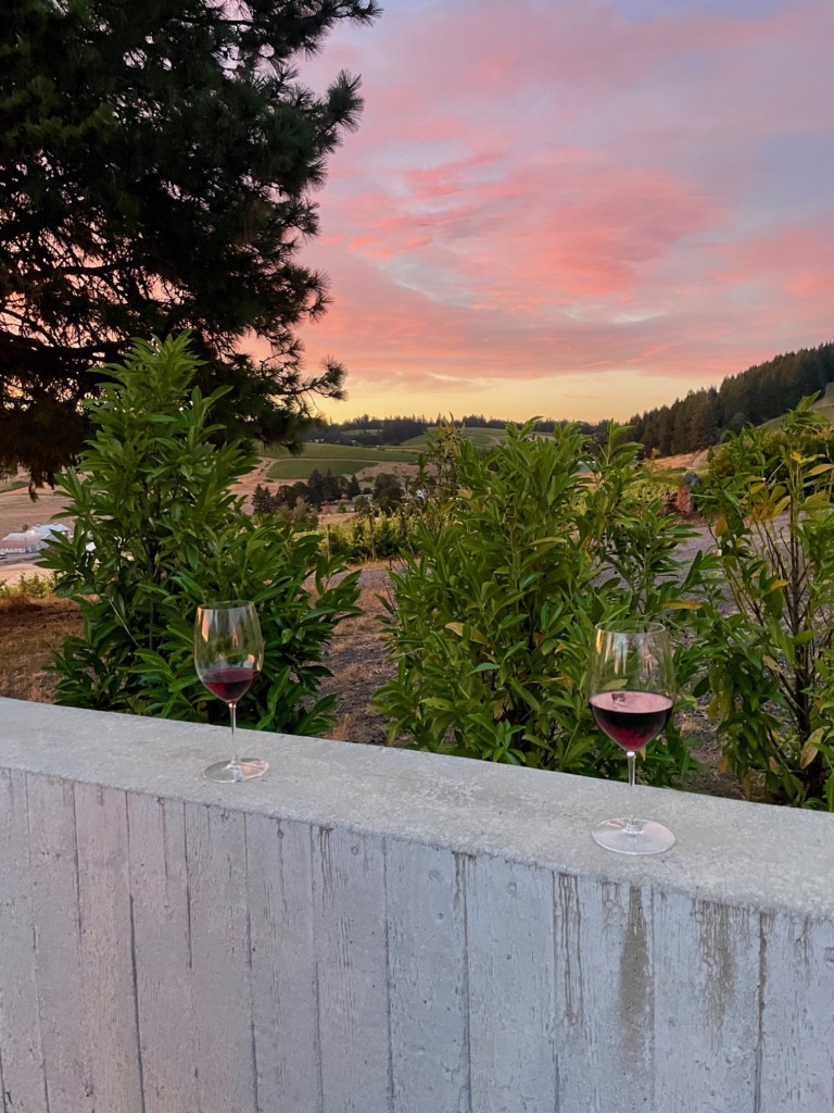 Two glasses of red wine at sunset with vineyard views at Deux Vert Vineyard in Oregon’s Willamette Valley