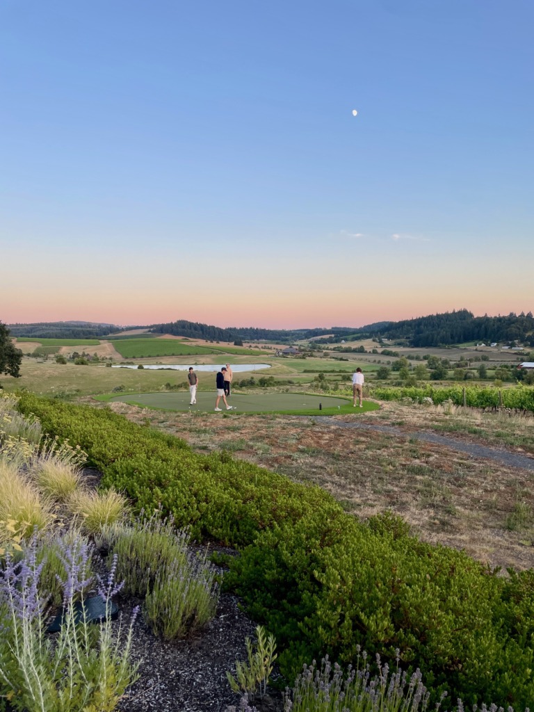 Guests playing golf at sunset overlooking vineyards and rolling hills at Deux Vert Vineyard in Oregon.