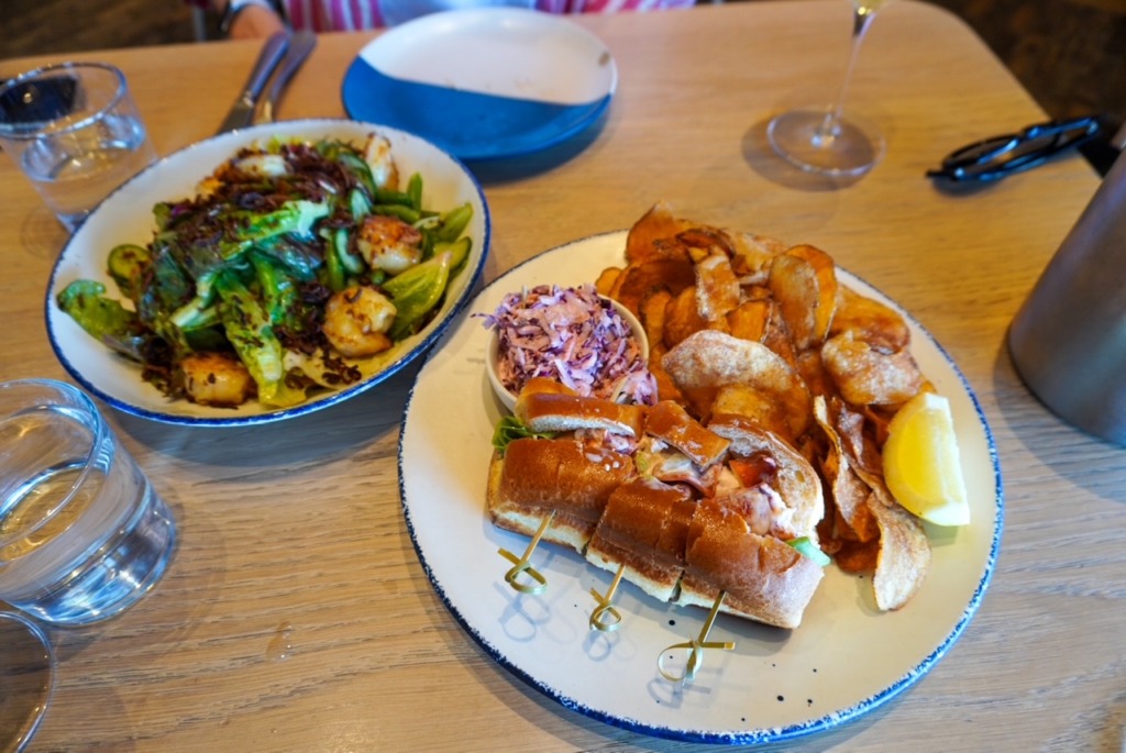 Lobster roll with house-made chips and slaw, served alongside a shrimp and greens salad at Straight Wharf Fish in Nantucket