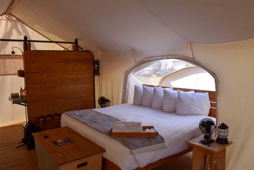 Interior of the Stargazer tent at Under Canvas Lake Powell featuring a cozy bed, lanterns, and a skylight for stargazing