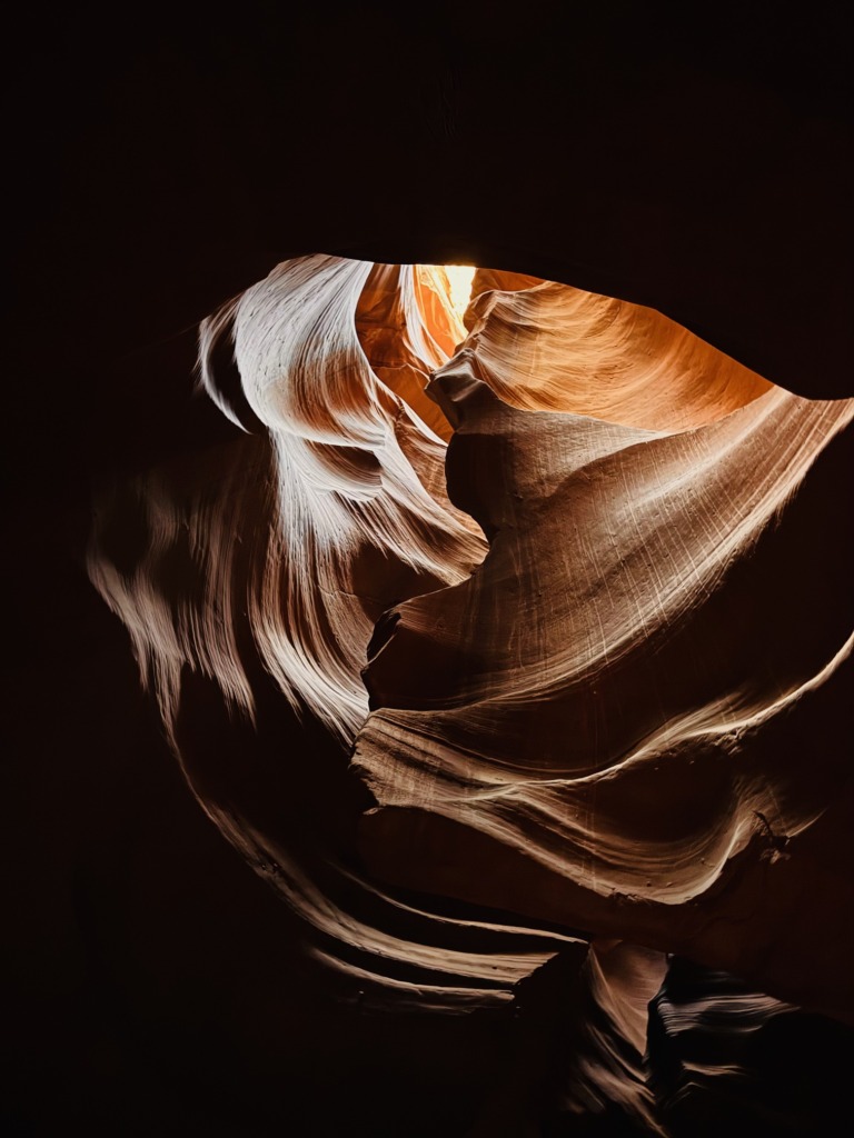 Sunlight streaming through sculpted canyon walls at Antelope Canyon, showcasing smooth sandstone layers