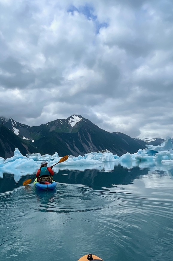 Kayaker paddling among blue icebergs at Bear Glacier Lagoon in Kenai Fjords National Park, Alaska