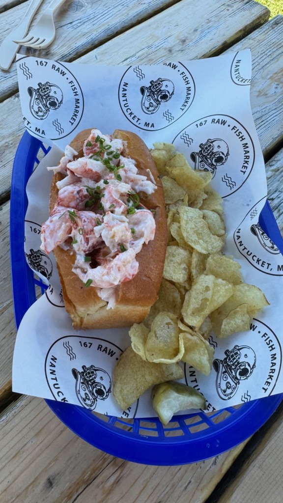 Lobster roll with chives and chips served in a basket lined with 167 Raw Fish Market paper in Nantucket, Massachusetts — one of the best summer food stops on the island