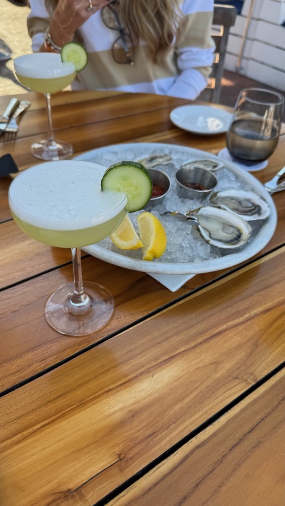 Two cucumber martinis and a tray of fresh oysters on ice at an outdoor restaurant table in Nantucket, Massachusetts — a classic summer vacation lunch on the island