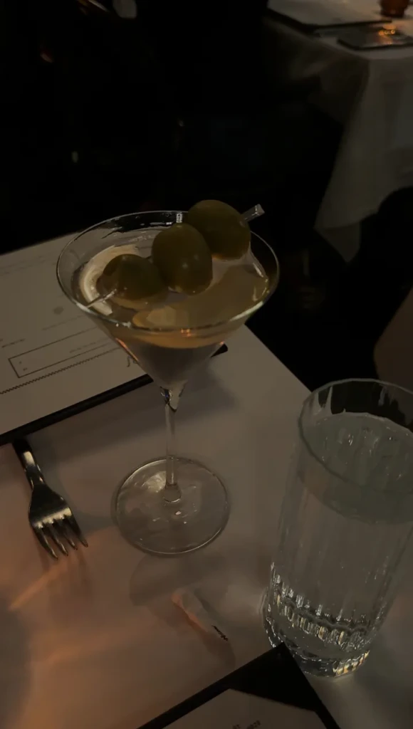 A dirty martini with three olives on a white tablecloth at a dimly lit restaurant in Jackson Hole, Wyoming